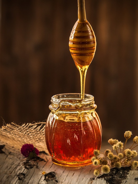 honey medus varva nuo šaukšto į stiklainį
